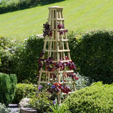 A wooden Snowdon Obelisk in a garden setting, featuring a pyramid shape with climbing plants.